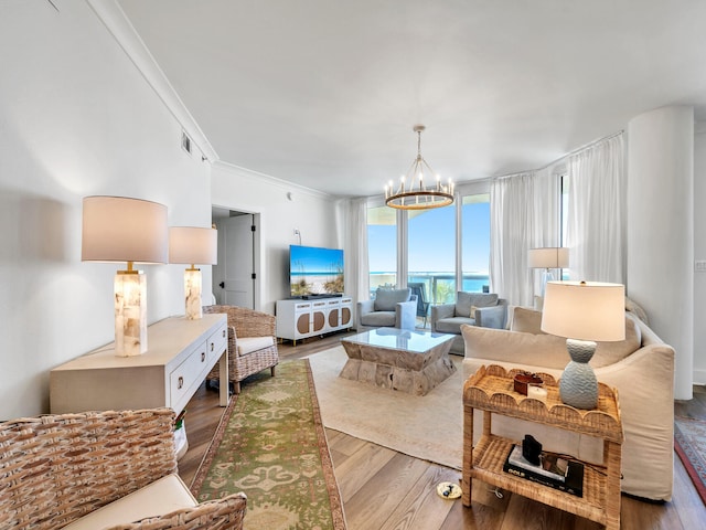 living room with hardwood / wood-style flooring, ornamental molding, and a notable chandelier