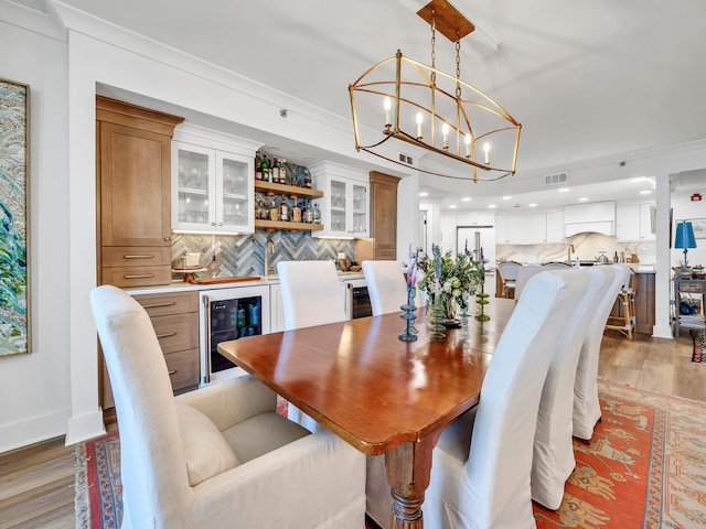 dining space with bar, wine cooler, and light wood-type flooring