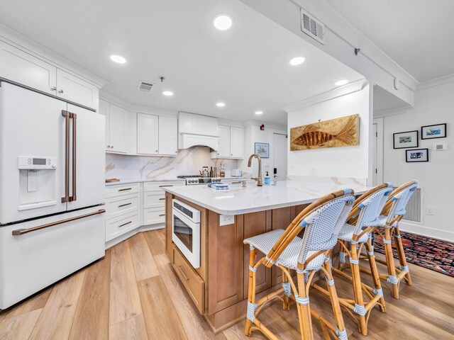 110 Gulf Shore Dr Unit 221, Destin, FL 32541 - kitchen with white appliances, light wood-style floors, white cabinetry, a kitchen bar, and recessed lighting