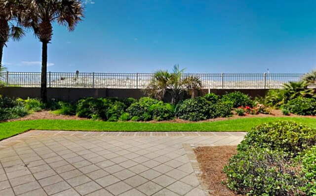 view of property's community with a patio, a water view, and a beach view