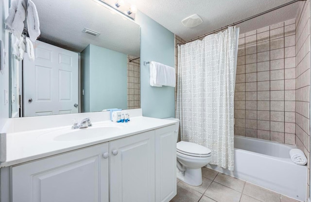 full bathroom featuring a textured ceiling, shower / bath combo with shower curtain, vanity, tile patterned floors, and toilet