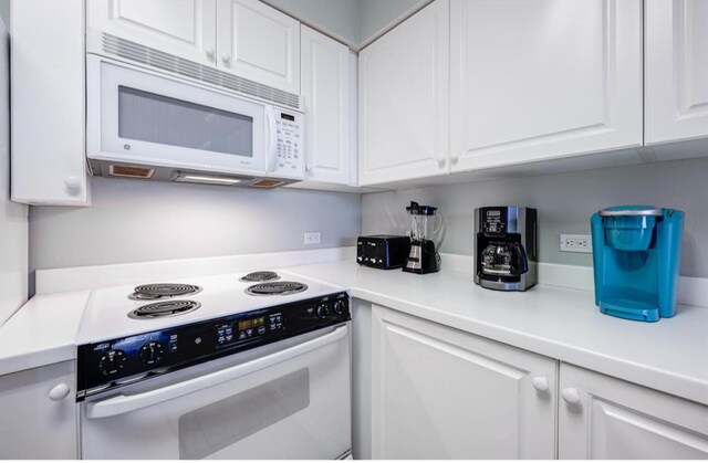 kitchen featuring white cabinets and white appliances