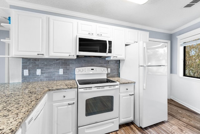 kitchen with light stone counters, ornamental molding, white appliances, wood-type flooring, and white cabinets