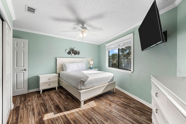 bedroom with dark hardwood / wood-style flooring, a textured ceiling, ornamental molding, ceiling fan, and a closet