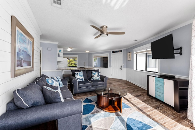 living room featuring a textured ceiling, dark hardwood / wood-style floors, ceiling fan, and crown molding