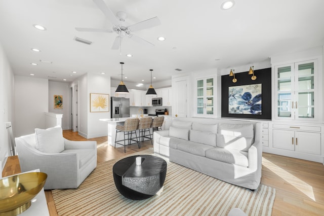 living room with ceiling fan and light hardwood / wood-style flooring