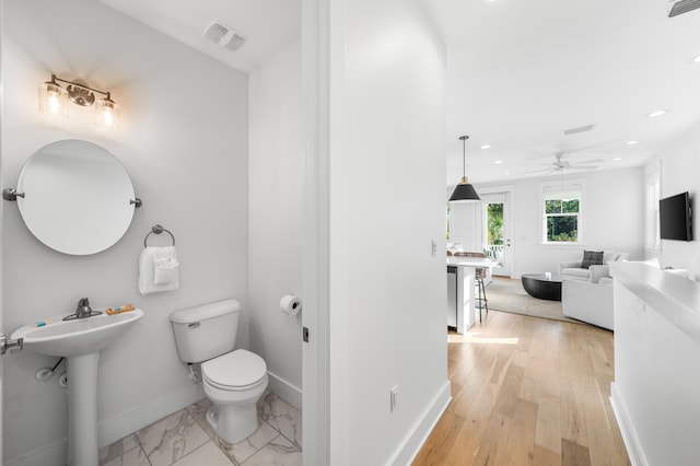 bathroom with hardwood / wood-style floors, ceiling fan, toilet, and sink