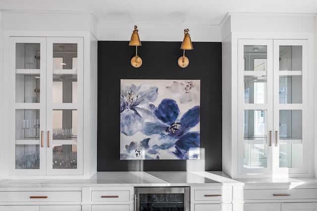 interior space featuring ornamental molding, light stone countertops, beverage cooler, white cabinets, and pendant lighting