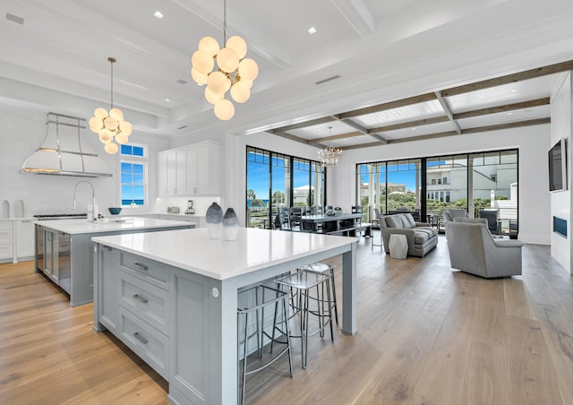 kitchen featuring light hardwood / wood-style flooring, a large island, pendant lighting, a notable chandelier, and exhaust hood