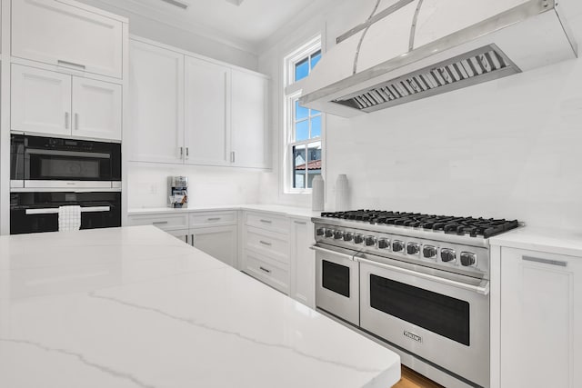 kitchen featuring white cabinetry, light stone countertops, ventilation hood, and range with two ovens