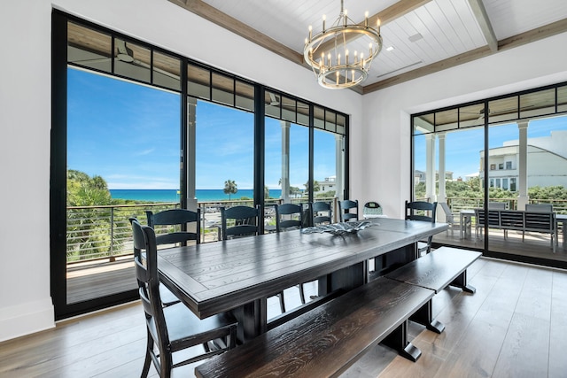 dining area with an inviting chandelier, hardwood / wood-style flooring, wooden ceiling, and a water view