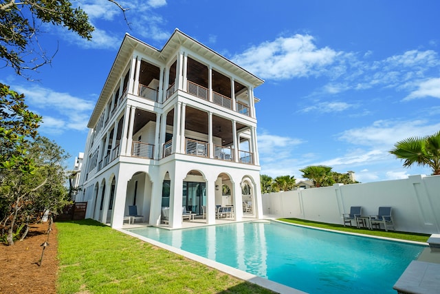 rear view of house with a fenced in pool, a patio, a lawn, and a balcony