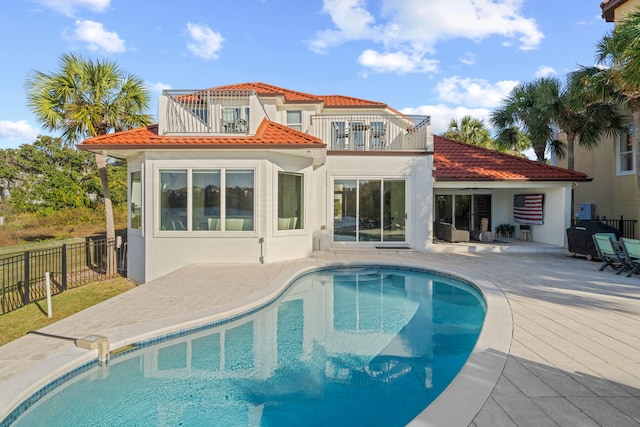 rear view of property featuring a balcony, a fenced in pool, and a patio