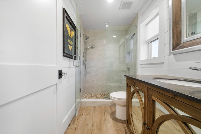 bathroom with hardwood / wood-style floors, a shower with shower door, vanity, and toilet