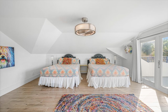 bedroom featuring light hardwood / wood-style flooring, lofted ceiling, and access to outside