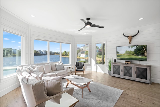 living room featuring light hardwood / wood-style floors, wood walls, and ceiling fan