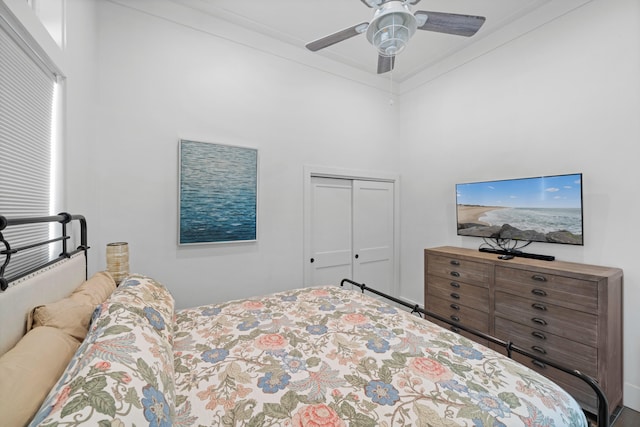 bedroom with a closet, a towering ceiling, ceiling fan, and crown molding