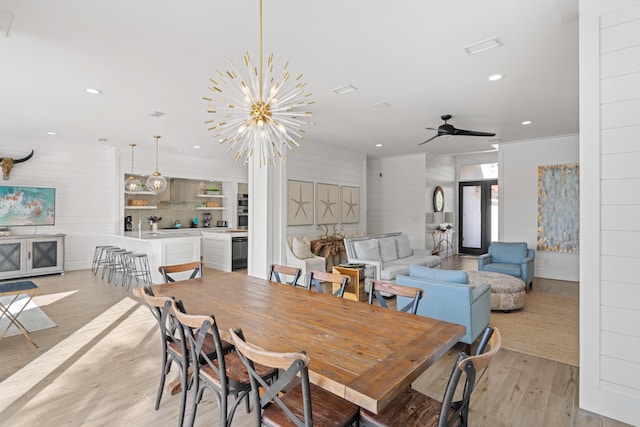 dining room with ceiling fan with notable chandelier and light wood-type flooring