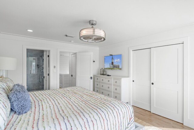 bedroom with a closet, light hardwood / wood-style floors, and crown molding