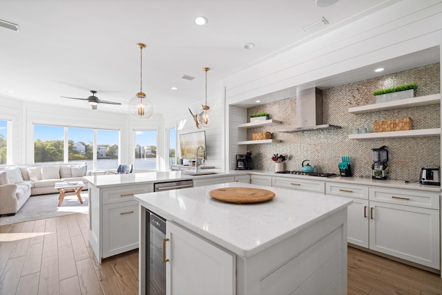 kitchen featuring decorative light fixtures, sink, light hardwood / wood-style floors, white cabinets, and a center island