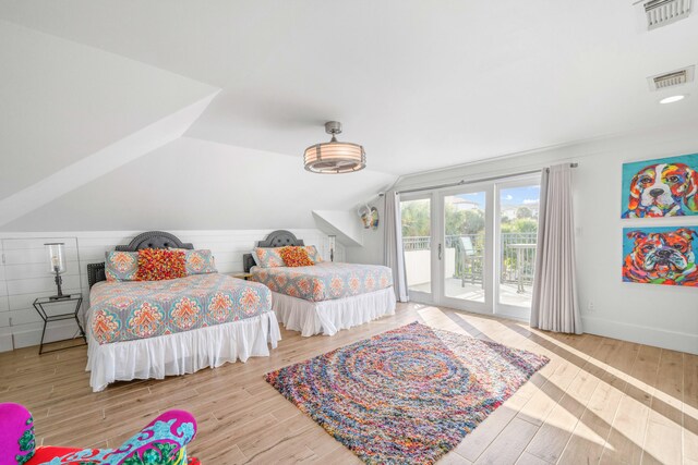 bedroom with access to exterior, light hardwood / wood-style flooring, and lofted ceiling