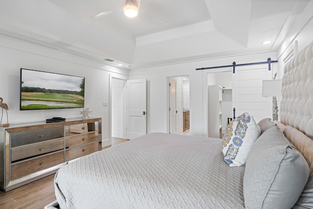 bedroom featuring ensuite bathroom, ceiling fan, hardwood / wood-style floors, a barn door, and a closet