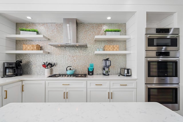 4639 Destiny Way, Destin, FL 32541 - kitchen featuring open shelves, wall chimney exhaust hood, stainless steel appliances, tasteful backsplash, and light stone countertops