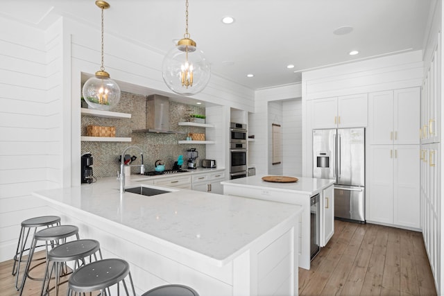 kitchen with stainless steel appliances, a breakfast bar, kitchen peninsula, hanging light fixtures, and light hardwood / wood-style flooring