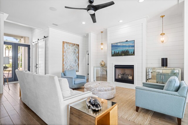 living room with a barn door, hardwood / wood-style flooring, ornamental molding, and a fireplace