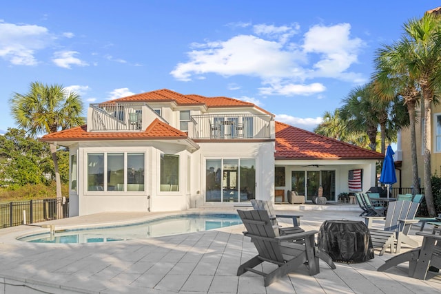 rear view of property featuring a balcony, a fenced in pool, and a patio