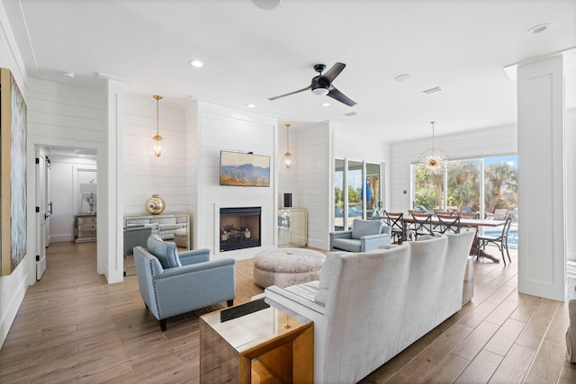 living room featuring wood-type flooring, ceiling fan, and wooden walls