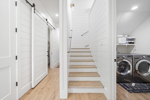 washroom with a barn door, light wood-type flooring, and washing machine and clothes dryer