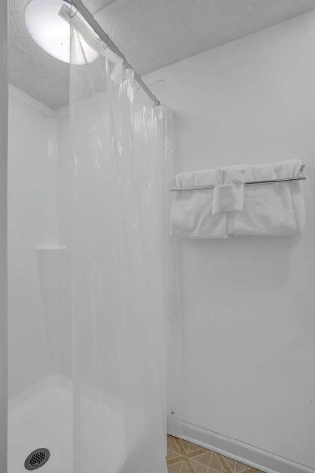 bathroom with a shower with shower curtain and a textured ceiling