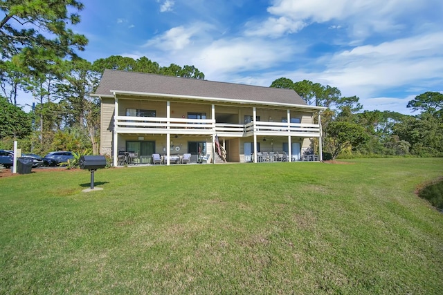 rear view of property featuring a lawn, a patio area, and a balcony