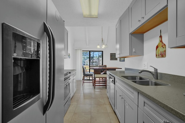 kitchen with gray cabinetry, an inviting chandelier, sink, light tile patterned floors, and appliances with stainless steel finishes