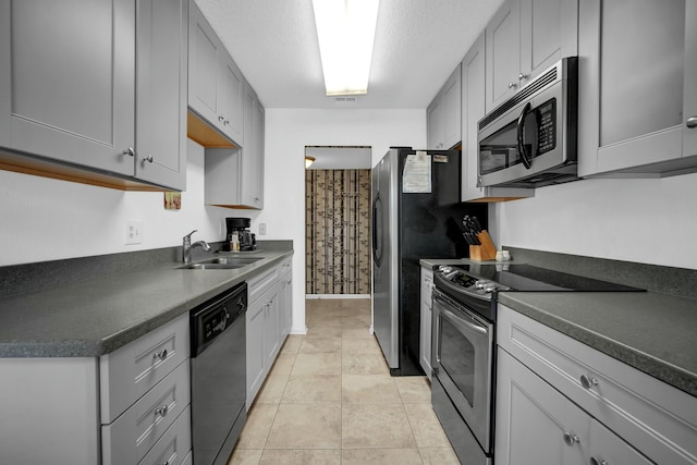 kitchen featuring appliances with stainless steel finishes, a textured ceiling, sink, light tile patterned floors, and gray cabinets