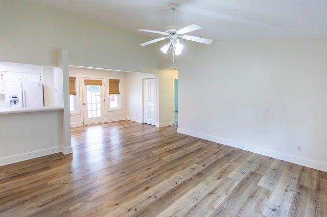 unfurnished living room with vaulted ceiling, ceiling fan, and light hardwood / wood-style flooring