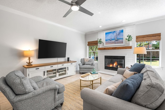 living room with ornamental molding, healthy amount of natural light, a large fireplace, light tile patterned floors, and a textured ceiling