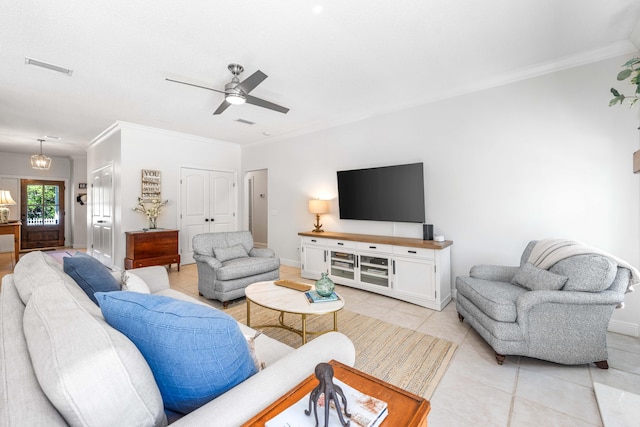 living area featuring light tile patterned floors, ornamental molding, a ceiling fan, and baseboards