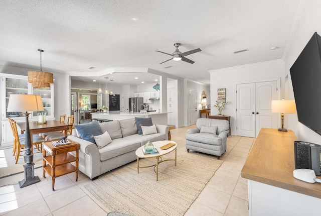 living room featuring ornamental molding, ceiling fan with notable chandelier, a textured ceiling, and light tile patterned floors