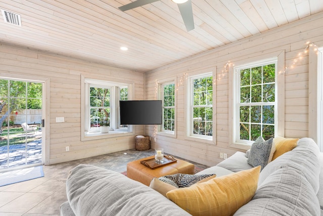 tiled living room with wood walls, a wealth of natural light, wood ceiling, and ceiling fan