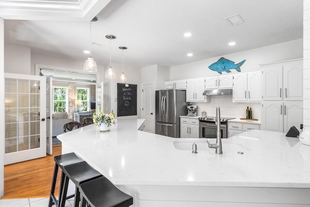 kitchen with white cabinetry, a breakfast bar, appliances with stainless steel finishes, tasteful backsplash, and light wood-type flooring