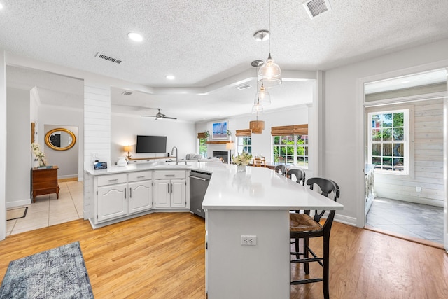 kitchen featuring dishwasher, light wood-type flooring, a breakfast bar area, open floor plan, and a textured ceiling