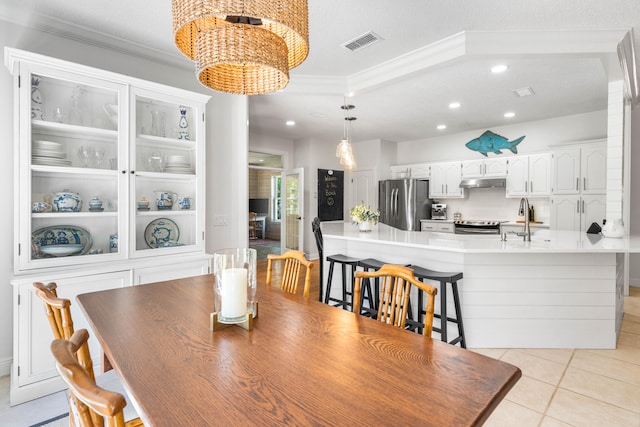 tiled dining area with sink, a textured ceiling, and crown molding