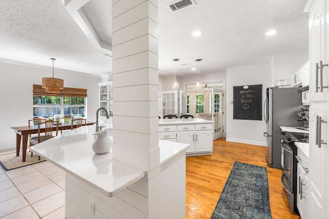 kitchen featuring stainless steel electric range, a textured ceiling, white cabinets, light countertops, and decorative light fixtures