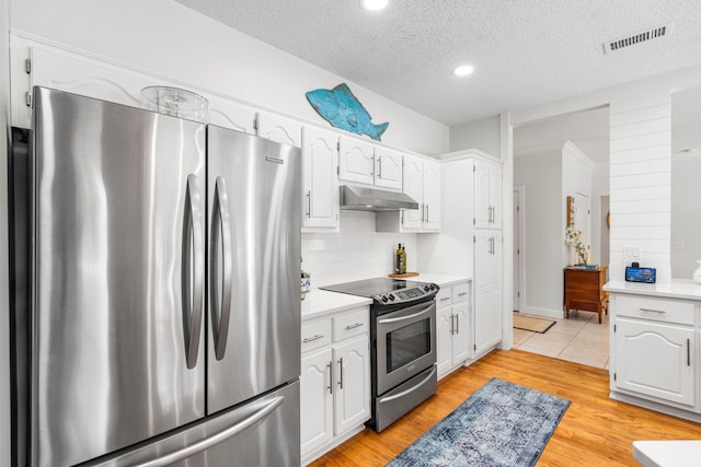 kitchen with light hardwood / wood-style flooring, appliances with stainless steel finishes, a textured ceiling, and white cabinets