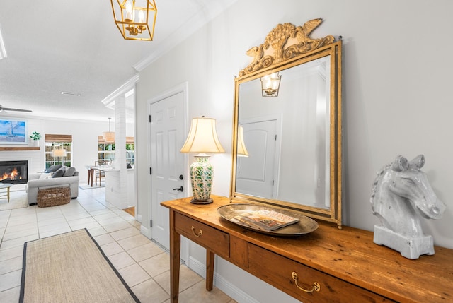 foyer with crown molding, a glass covered fireplace, light tile patterned floors, and baseboards