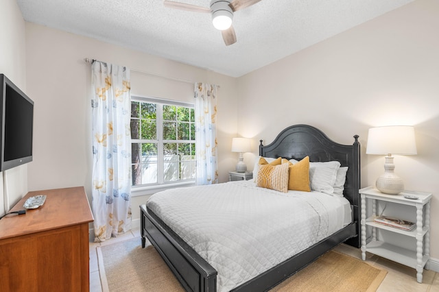 bedroom with ceiling fan, a textured ceiling, and light tile patterned floors