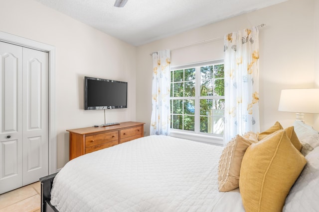 bedroom featuring a closet, light tile patterned floors, a textured ceiling, and ceiling fan