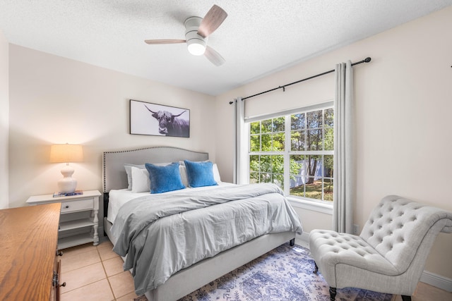 bedroom with a textured ceiling, ceiling fan, and light tile patterned flooring